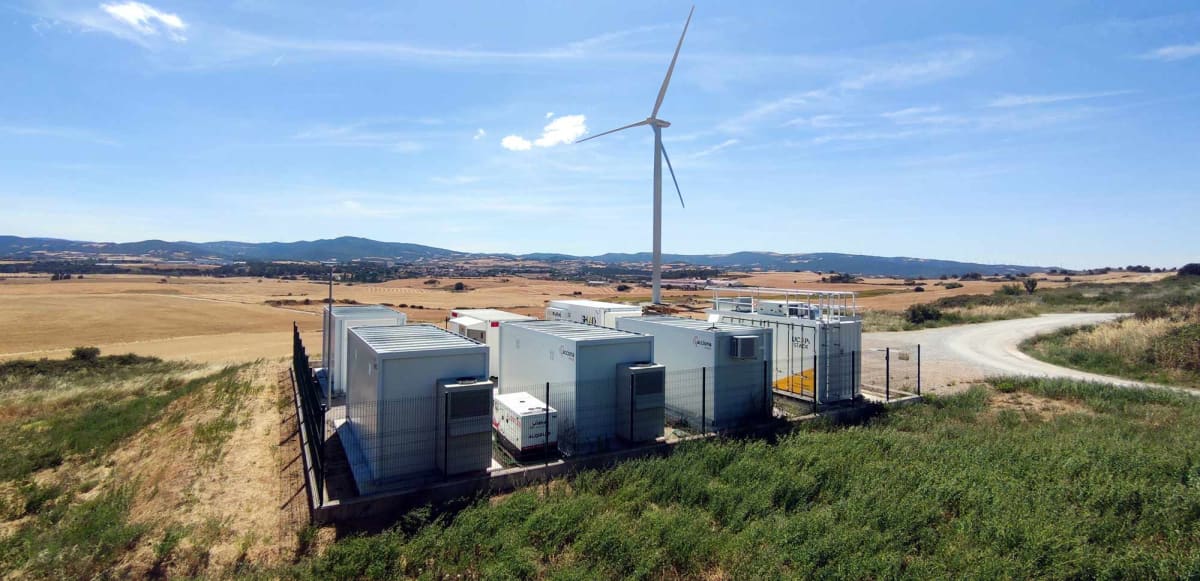 Large battery storage containers and solar panels at renewable energy facility in Spain