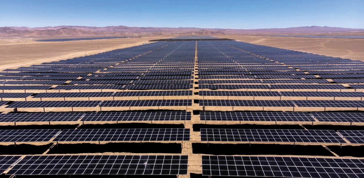 Expansive solar panel farm stretching across Chilean desert landscape under bright blue sky