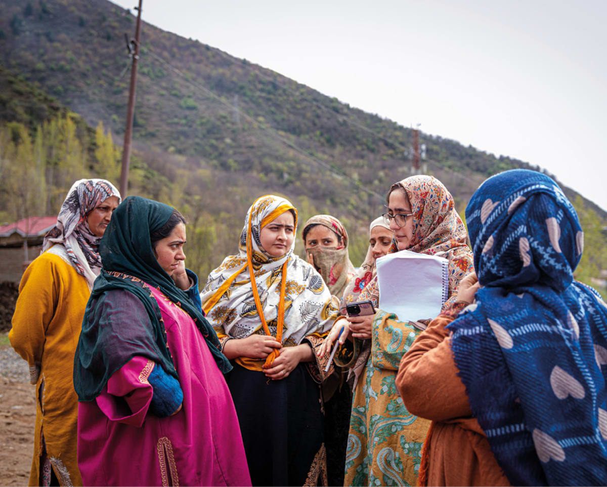 Solar panels installed on rooftops in rural Indian village with families nearby