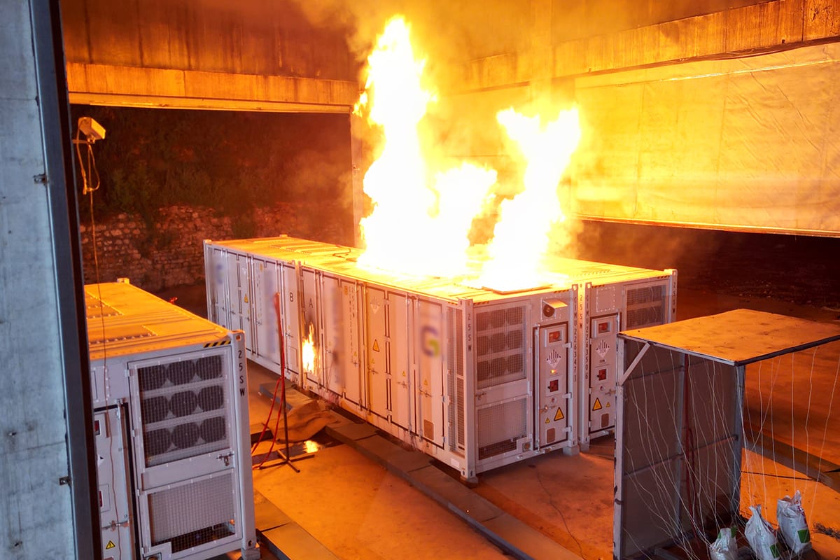 Large white industrial battery storage container during extreme safety fire testing conditions