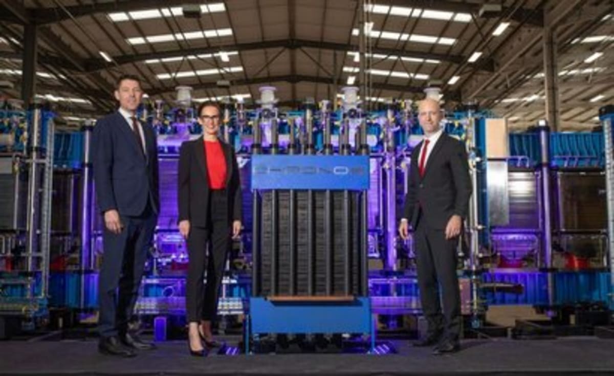 Modern electrolyzer manufacturing facility producing green hydrogen equipment with British flag visible