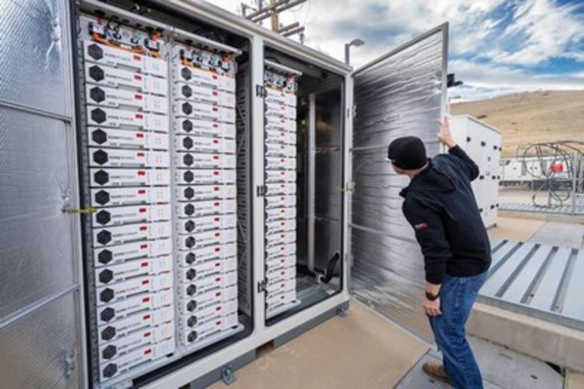 Large-scale battery storage facility with rows of white containers against California sunset sky