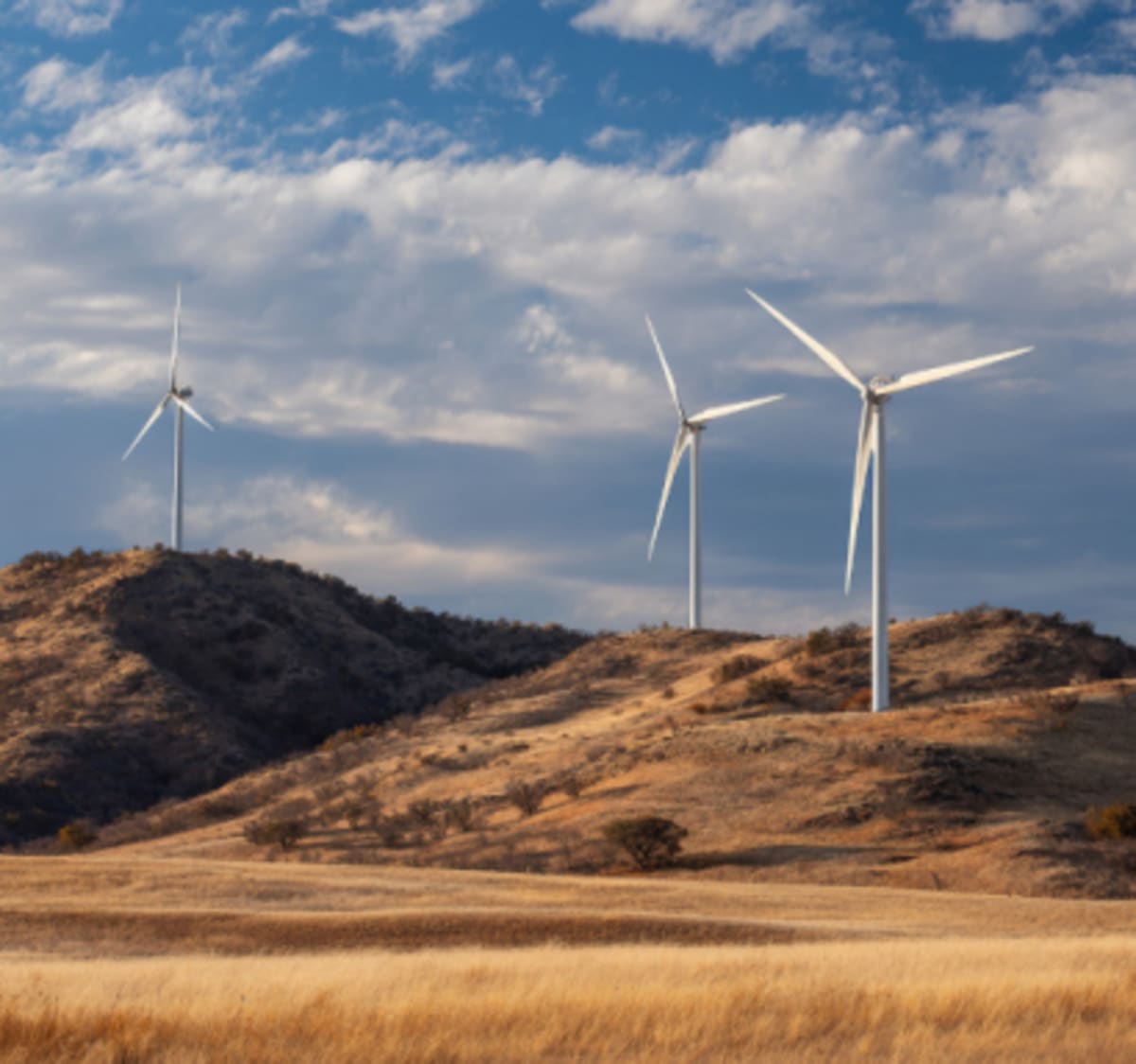 Modern white wind turbines spinning against blue sky generating renewable clean energy worldwide