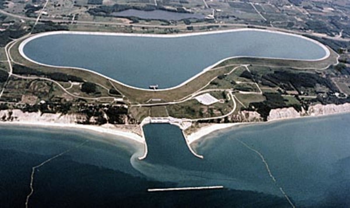 Aerial view of pumped storage hydropower reservoir with water flowing through turbines generating clean energy