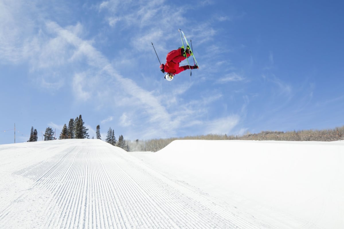 Alex Ferreira performing aerial freeski halfpipe trick against snowy mountain backdrop at Olympics
