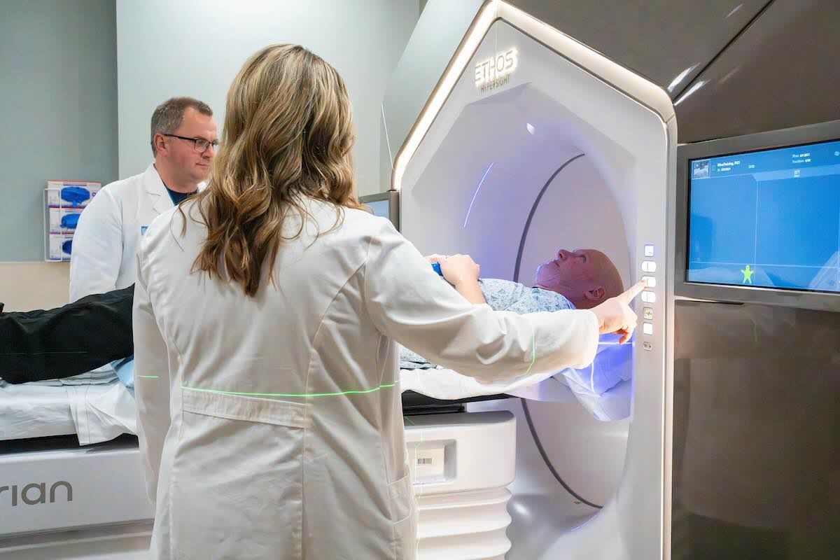 Medical professional operating advanced radiation therapy equipment in modern cancer treatment facility