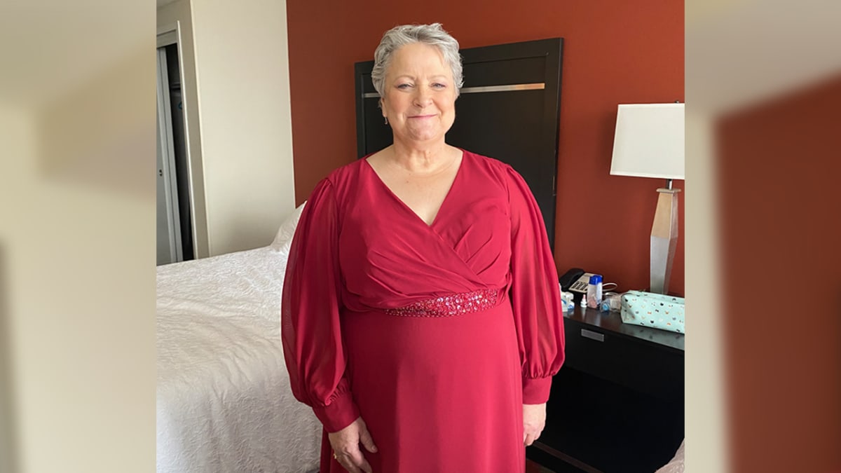 Smiling woman in her sixties standing outdoors, representing cancer survivor finding peace after treatment