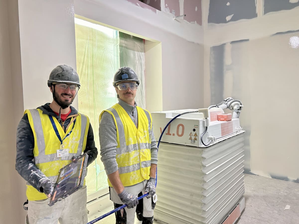 White plastering robot spraying walls automatically inside hospital construction site building interior