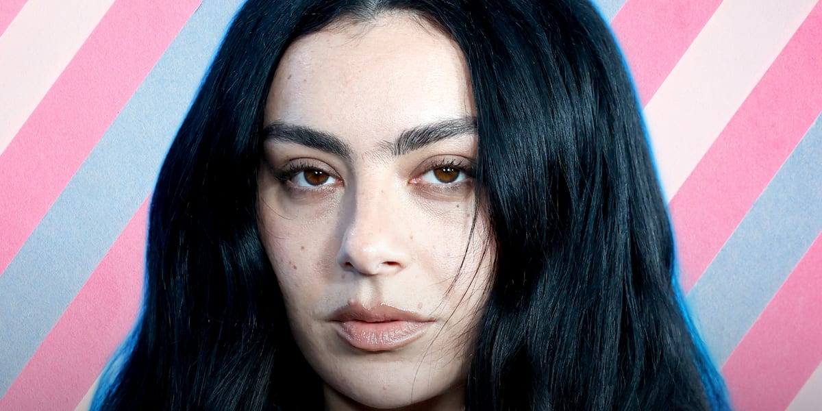 Pop star Charli XCX performing on stage with colorful lighting at concert venue