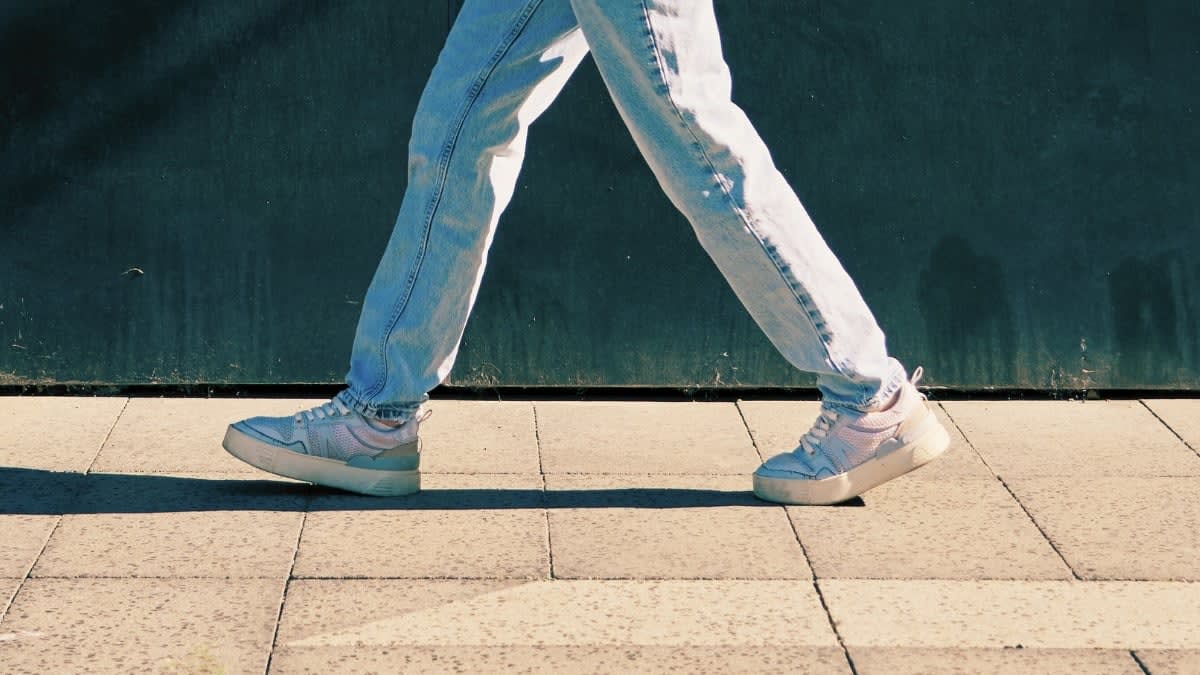 Person walking outdoors tracking steps on fitness watch while enjoying sunny day