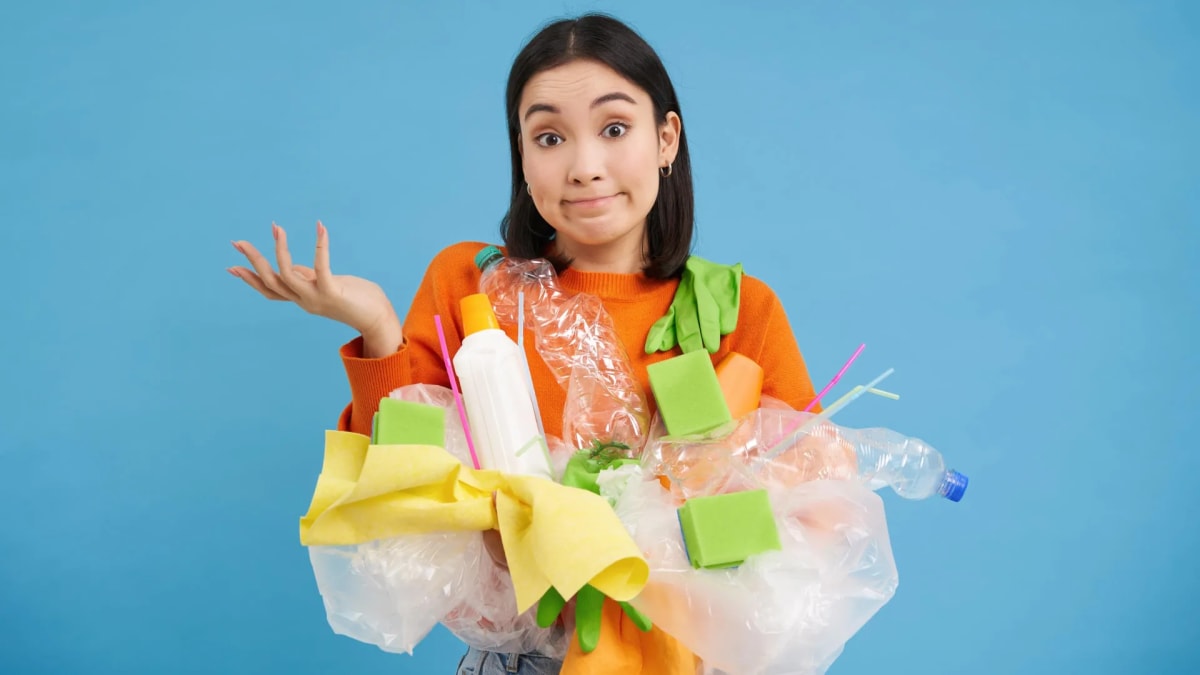 Person placing recyclable items into blue recycling bin with reusable containers nearby