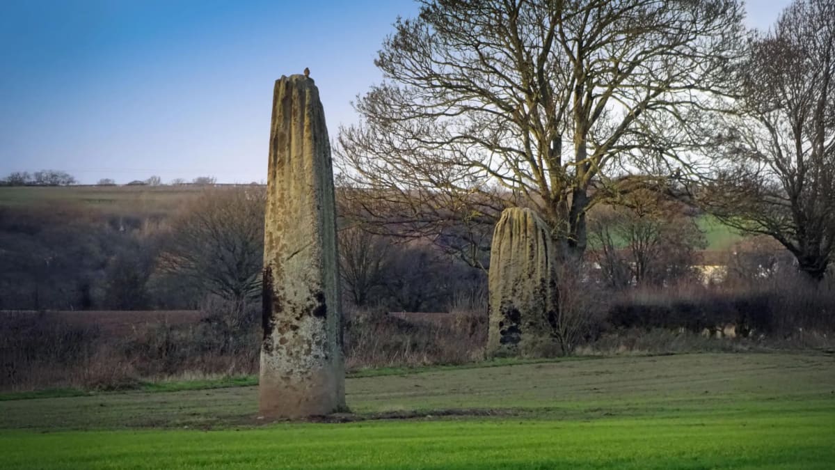 Tall prehistoric stone monuments called the Devil's Arrows standing in green Yorkshire countryside