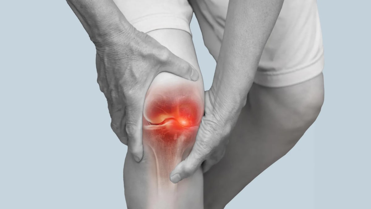 Person wearing knee brace while exercising in warm water pool for arthritis relief