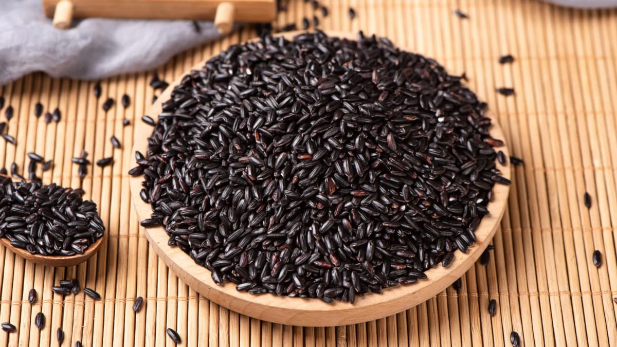 Black and green rice grains displayed next to white rice showing colorful pigmented varieties