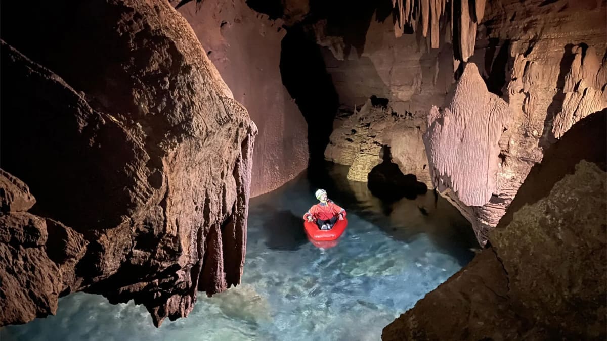 Researcher on inflatable raft inside flooded limestone cave at Grand Canyon with mapping equipment