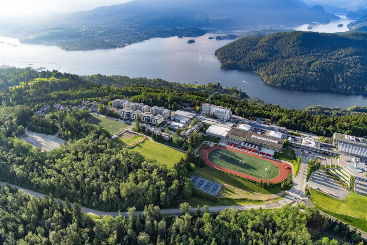 Simon Fraser University staff standing in front of biomass heating plant on Burnaby Mountain campus