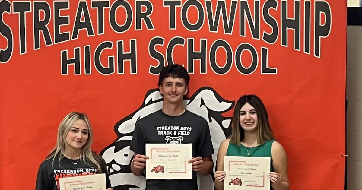Group of smiling high school students holding achievement certificates in school hallway