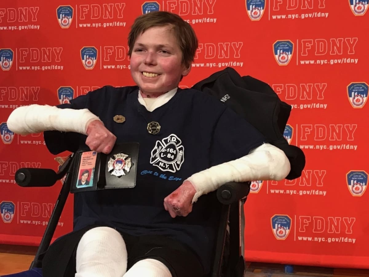 Young man in wheelchair smiling at ribbon-cutting ceremony for his new accessible home