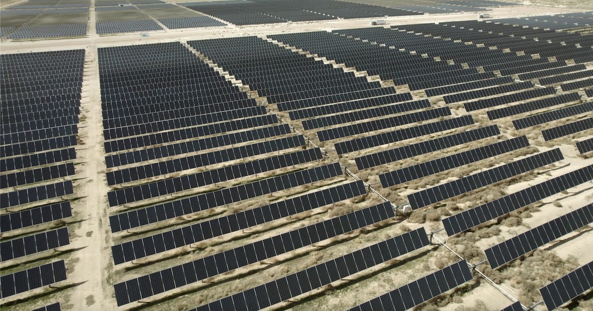 Wide view of solar panel arrays stretching across sunny Utah landscape under clear blue sky