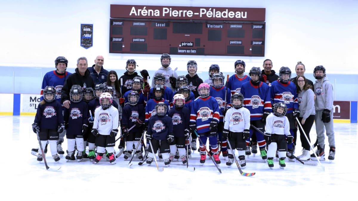 Vinnie Matteo standing at ice rink with hockey equipment helping young participants