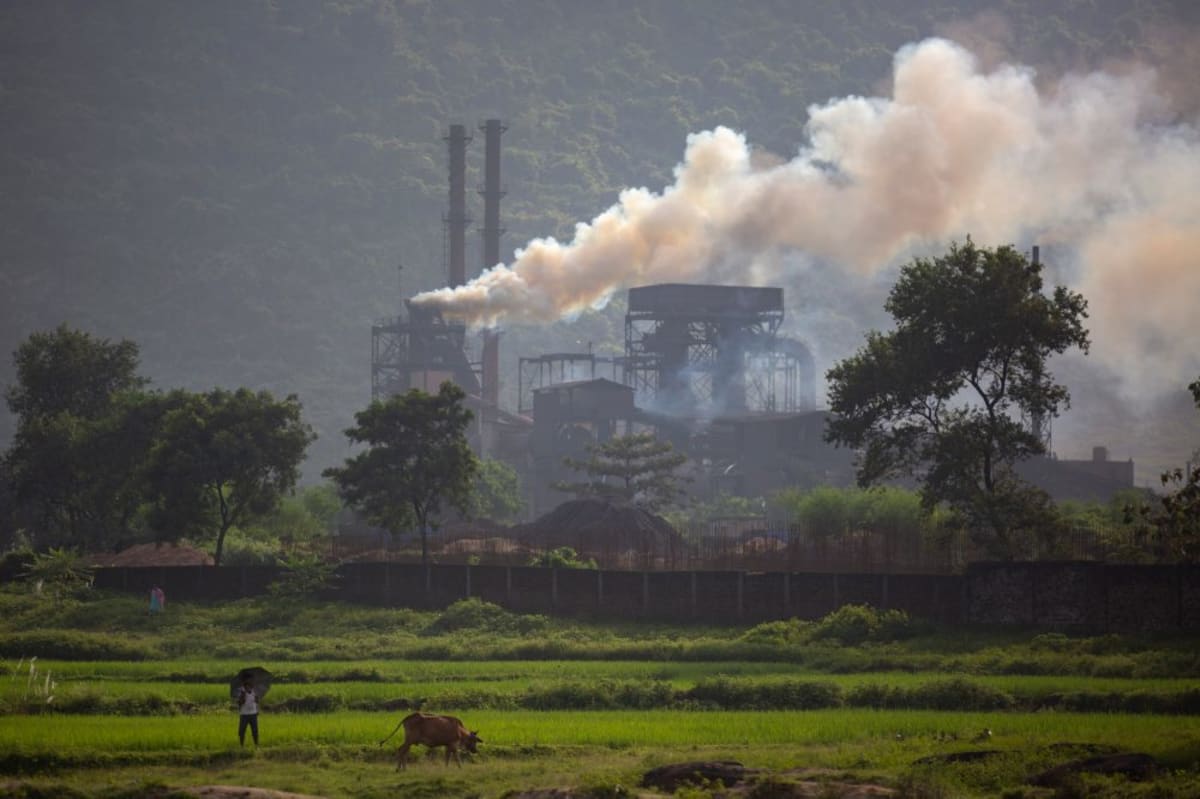 Solar panels and wind turbines powering steel manufacturing facility in India during sunny day