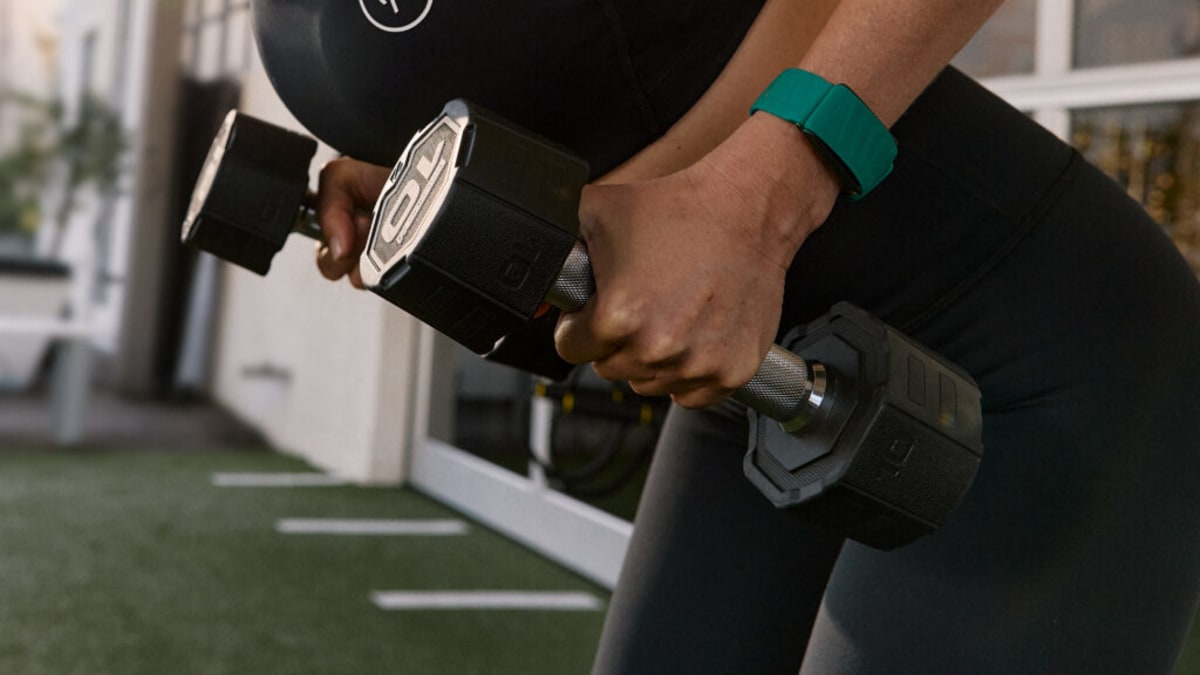 Person wearing Whoop fitness tracker wristband checking health data on smartphone screen