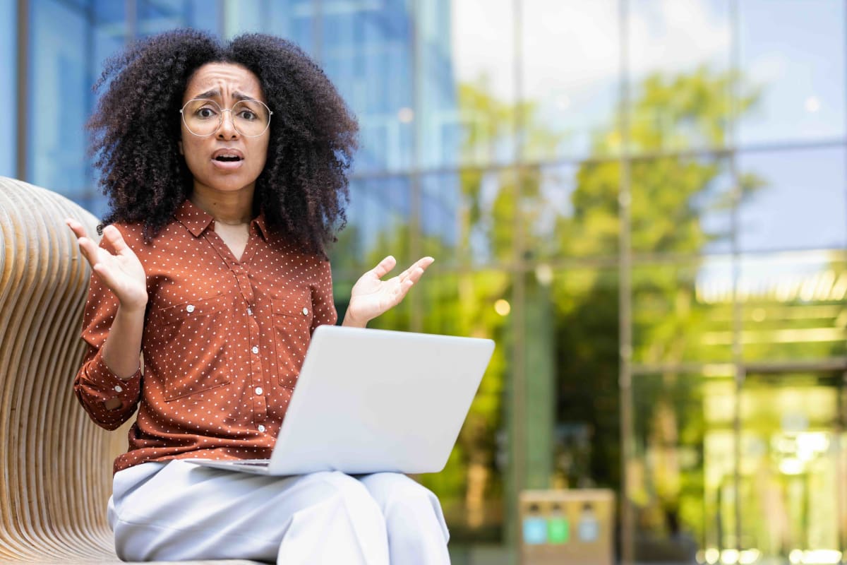 Professional woman smiling confidently while working on laptop in bright, hopeful office setting