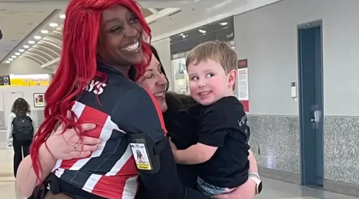 Waitress Brittany Bell holding smiling toddler in airport restaurant while working her shift
