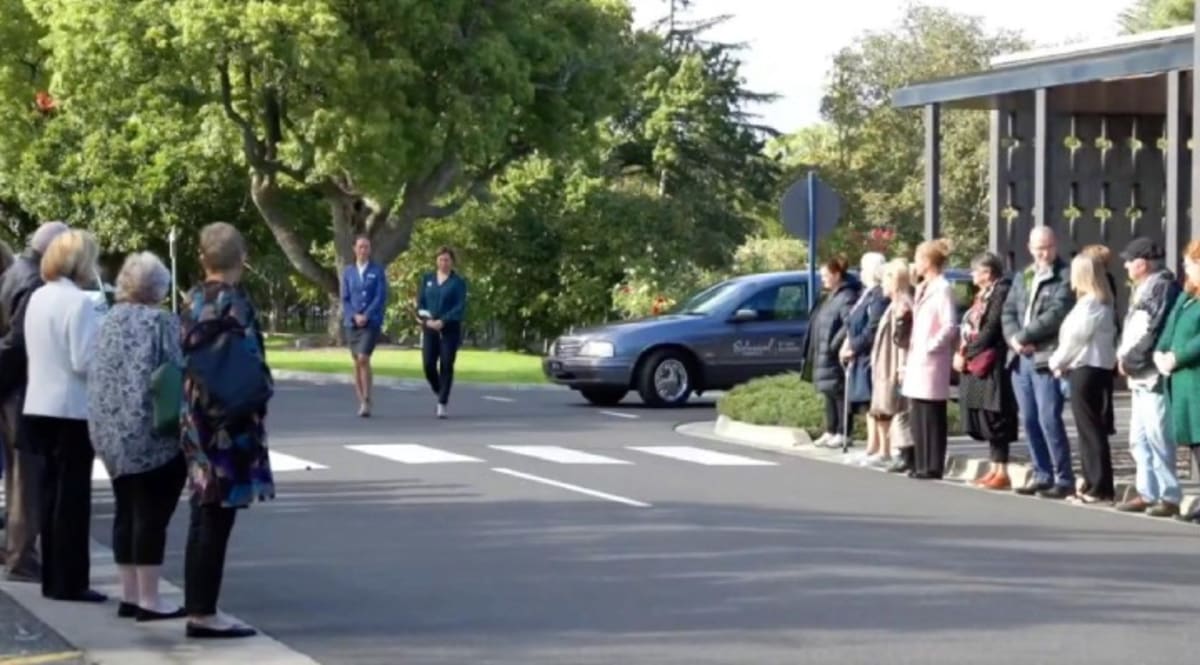 Mourners gather outside Springvale Botanical Cemetery chapel honoring stranger Michael Purcell in Melbourne