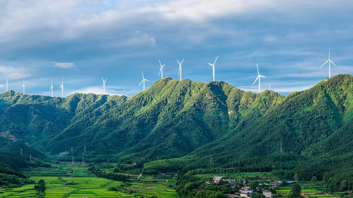 Massive white wind turbines spinning across rolling hills in China generating clean electricity