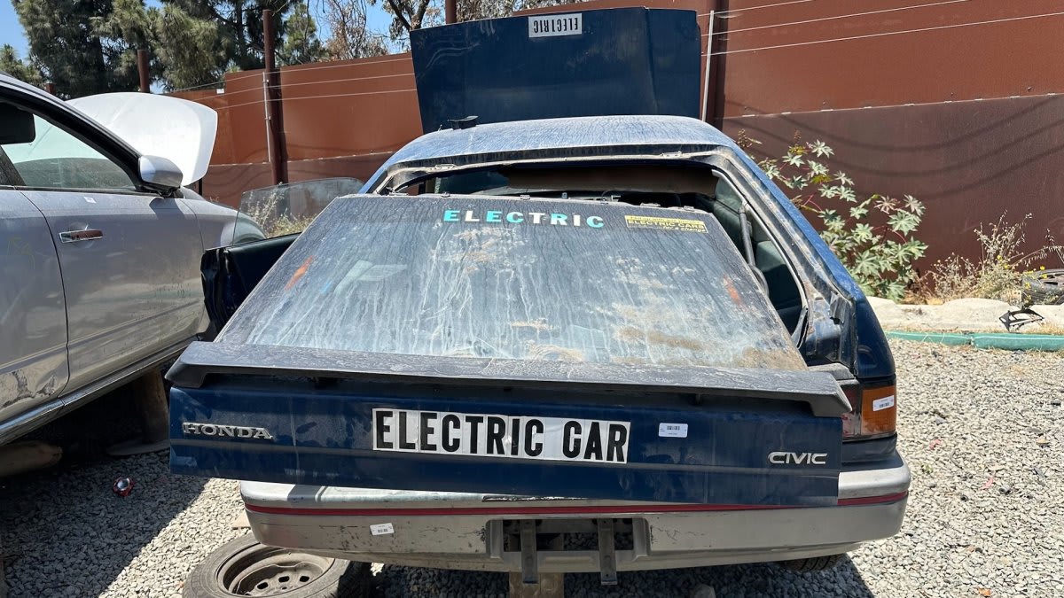 Rusted first-generation Honda CRX with homemade electric vehicle conversion in California junkyard