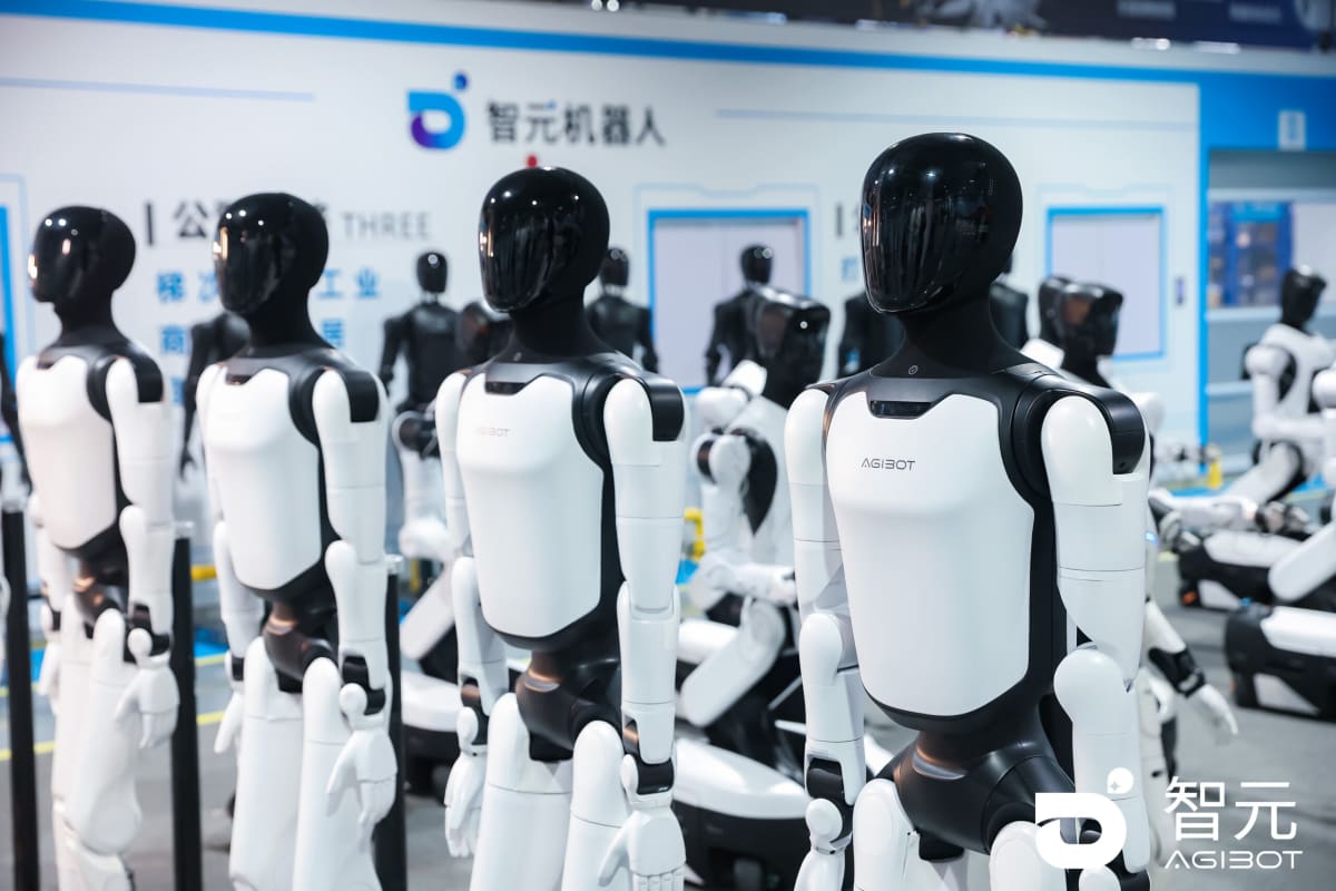 AGIBOT humanoid robot standing between company executives in modern technology facility