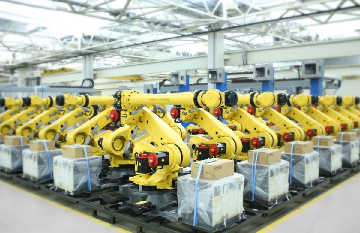 Modern industrial robots working on manufacturing assembly line in large factory facility
