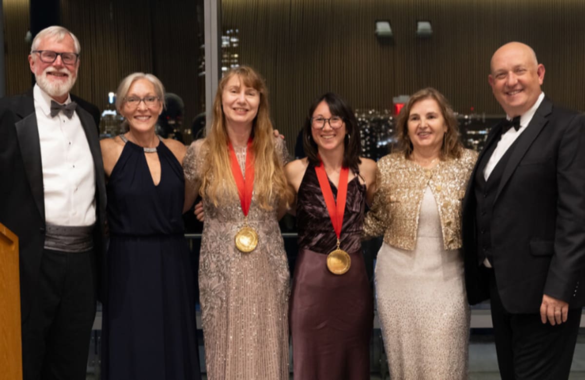 Two women roboticists standing with colleagues at the 2025 Women in Robotics Gala ceremony