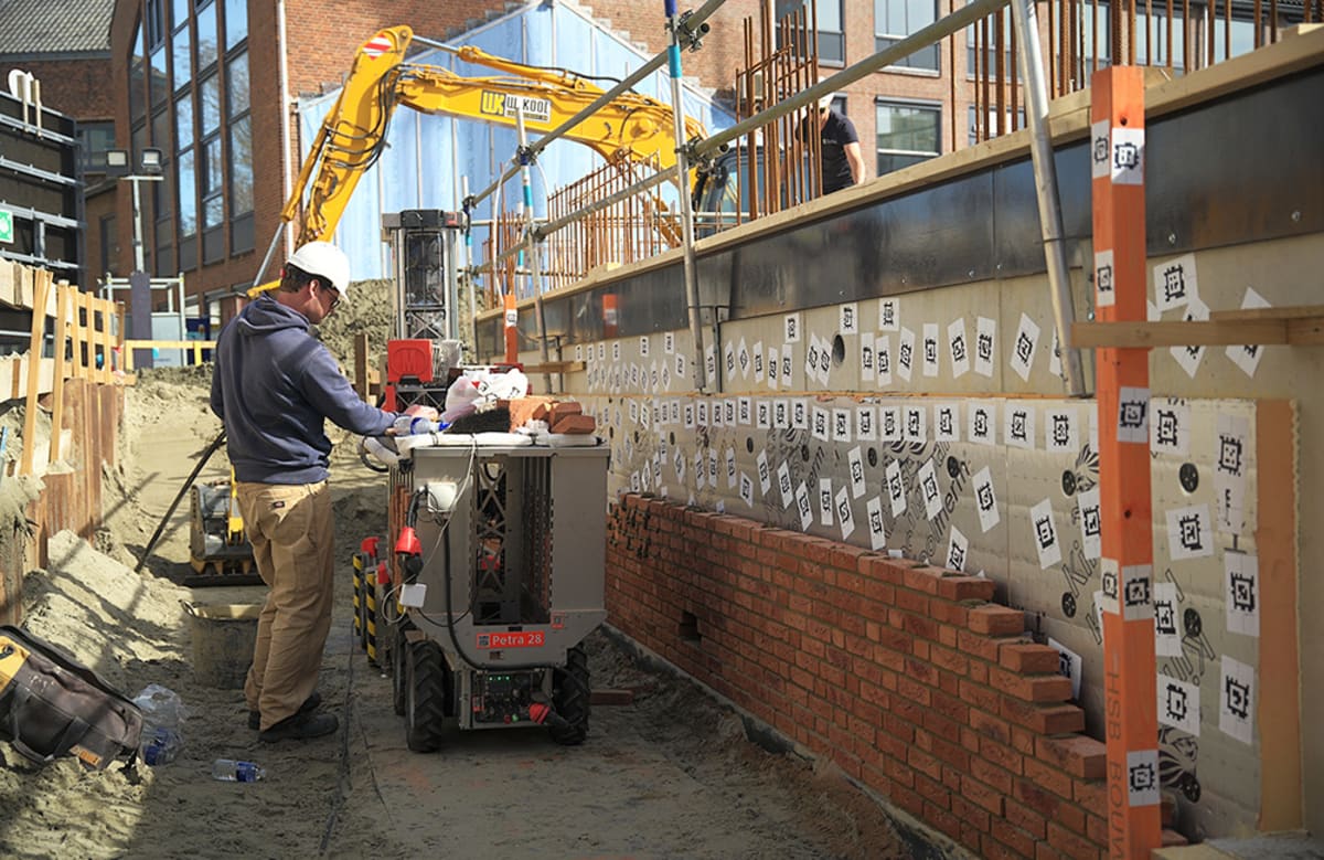Autonomous electric robot laying bricks with precision on active construction site in Netherlands