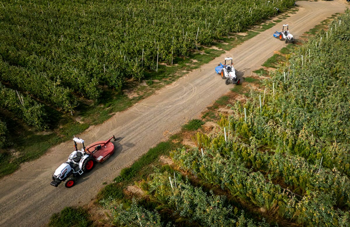 Autonomous tractor navigating tight turns between rows of fruit trees in orchard setting