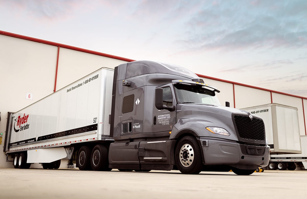 White autonomous semi-truck driving on highway with sensor equipment visible on cab