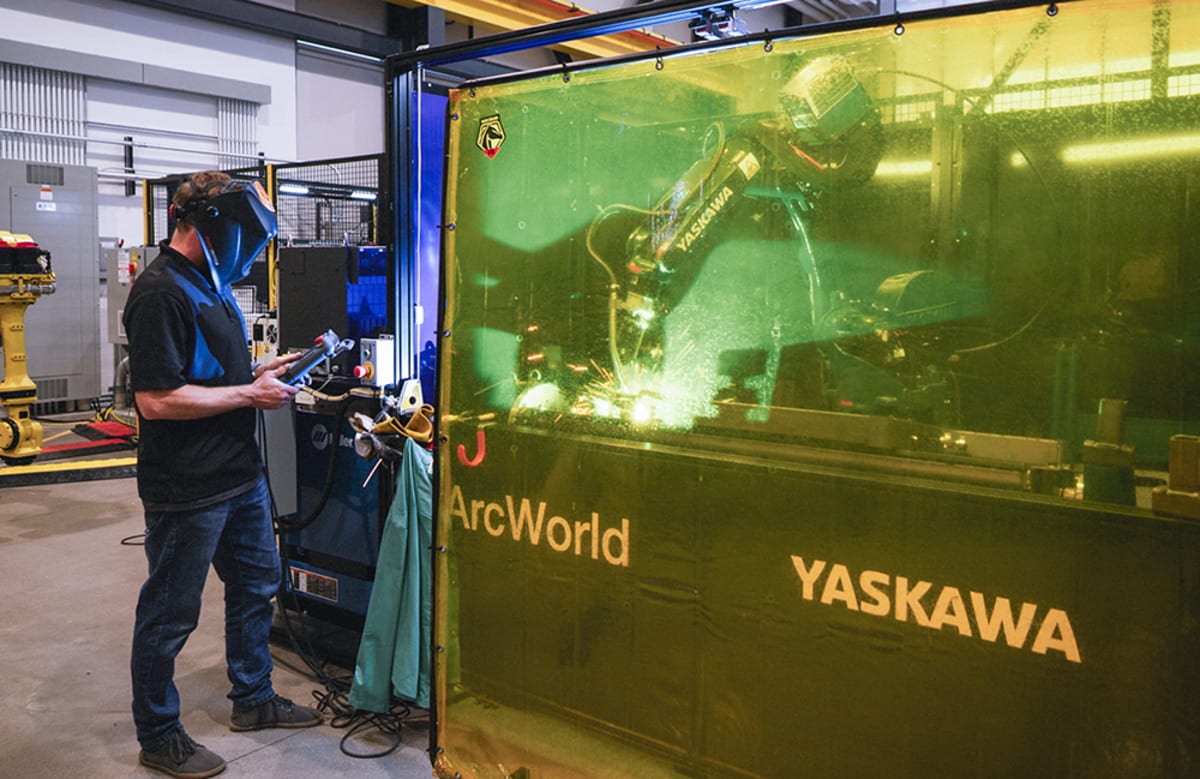 Advanced robotic equipment inside modern military manufacturing facility with workers collaborating nearby