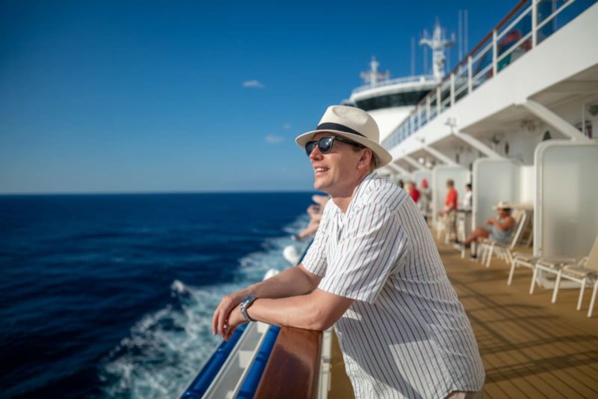 Cruise ship docked at Alaska terminal connecting to shore power infrastructure with mountains in background