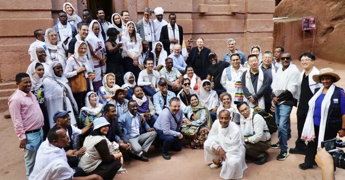 Ancient stone church carved into red volcanic rock in Lalibela, Ethiopia, surrounded by visitors