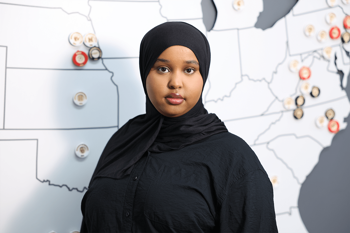 Hafso Ibrahim working at computer desk with headset during cybersecurity internship at Nelnet