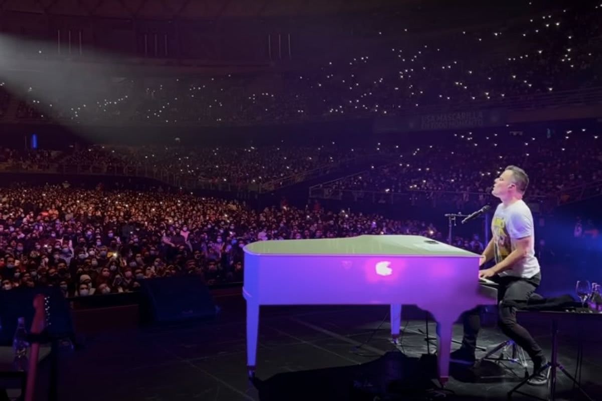 Marc Martel performing at piano with crowd of thousands singing along at concert