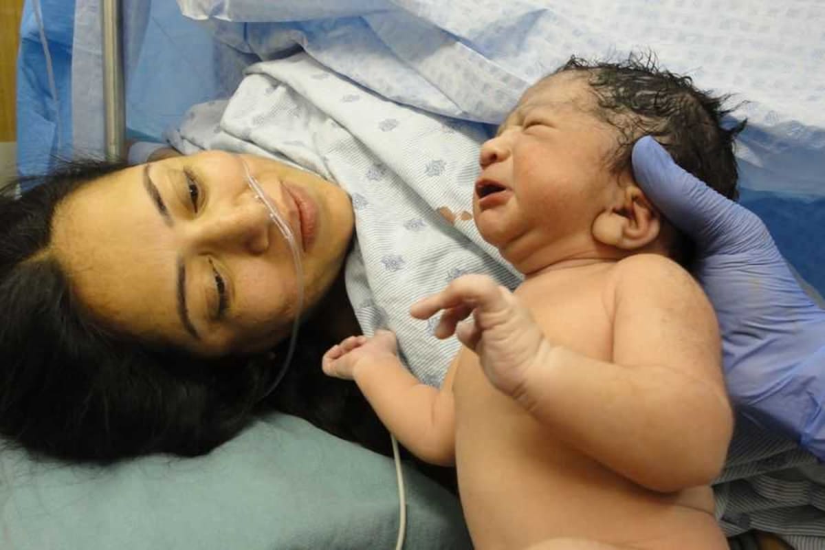 Newborn baby wrapped in blanket representing successful emergency delivery and survival