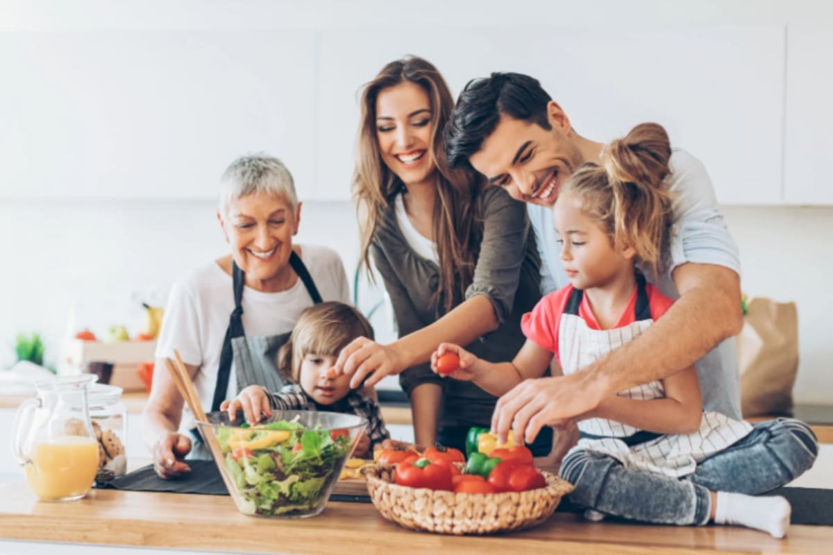 Three generations of family members cooking and spending time together in a sunny kitchen
