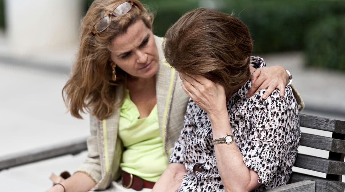 Elderly woman with Alzheimer's showing joy while talking with her daughter in waiting room