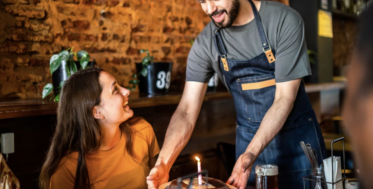 Woman overcome with emotion looking at lit birthday candles on dessert plate