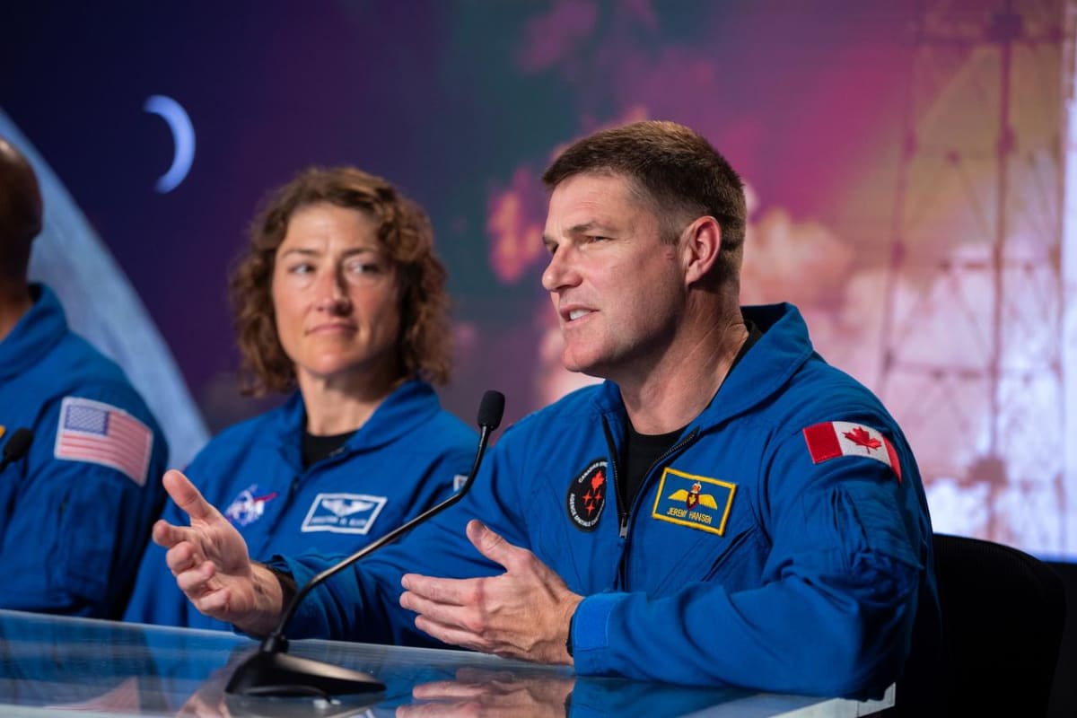 Canadian astronaut Jeremy Hansen in space holding mission patch with seven Indigenous sacred animals