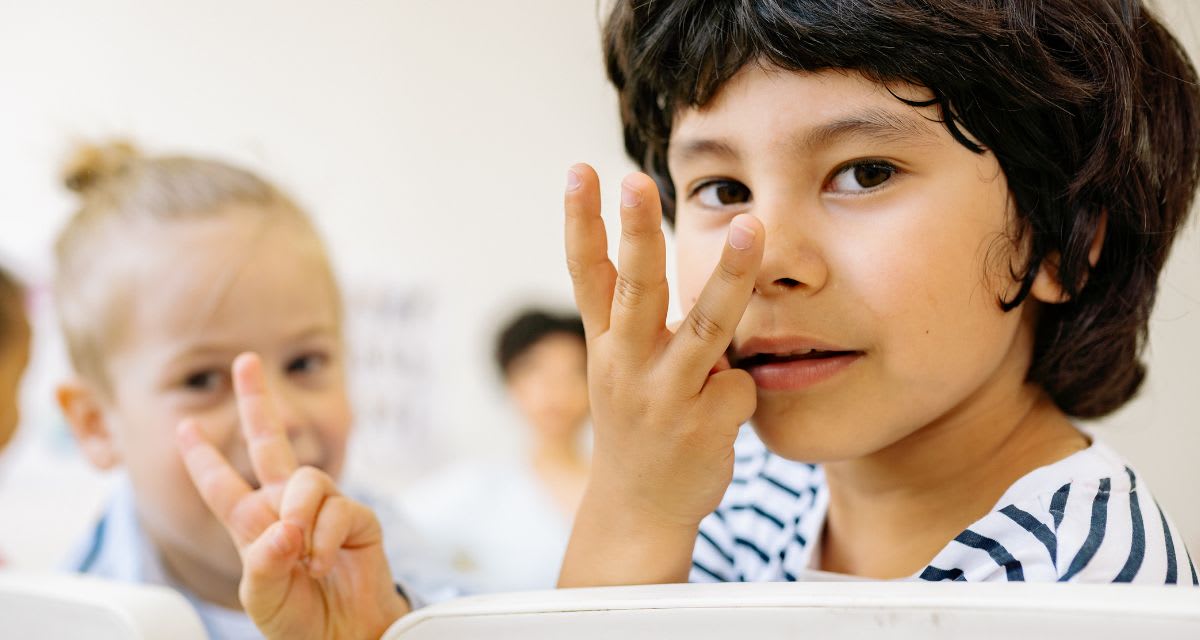Young elementary school students learning and practicing American Sign Language together in classroom
