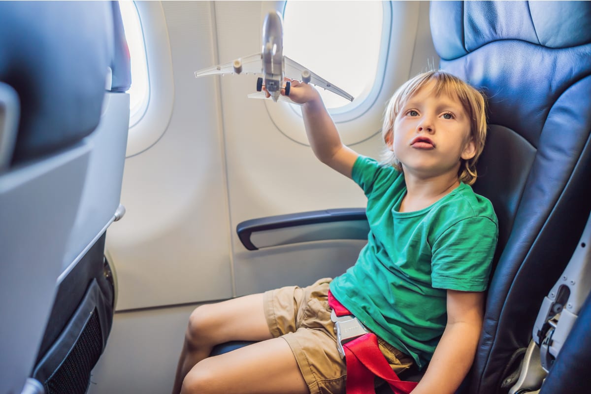Man sitting in airplane aisle seat next to young child on commercial flight