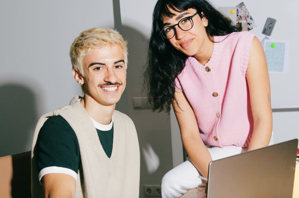 Young professional with pink hair working happily on laptop at home